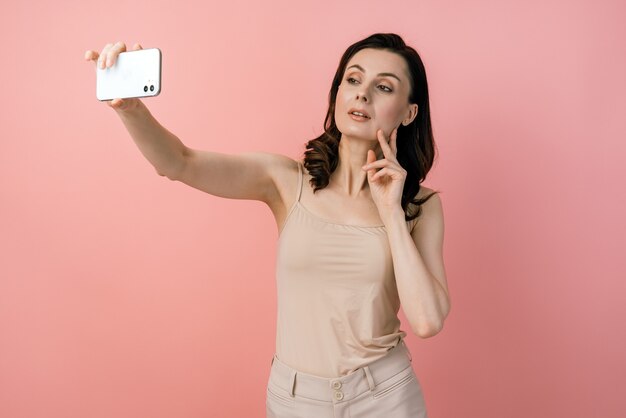 Attractive, young girl posing taking a selfie shot on mobile phone