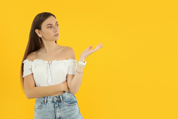 Attractive young girl stands on a yellow background