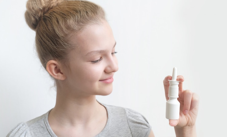 Attractive young girl using nasal spray