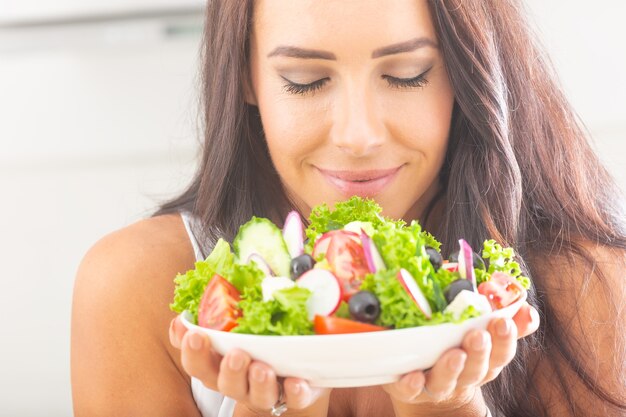 Attractive young and happy woman eating vegetable salad.