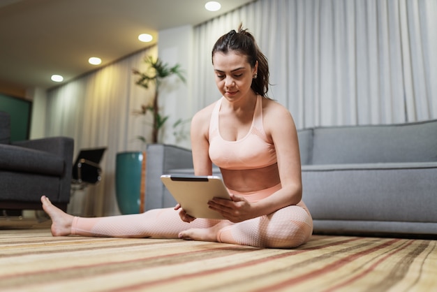 Attractive young Latin woman doing yoga stretching yoga online at home.