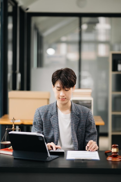 Attractive young lawyer in office Business man and lawyers discussing contract papers laptop and tablet with brass scale on desk in modern office Law legal services advice