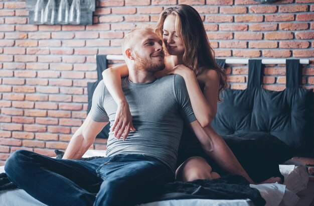 Attractive young lovers have a couple playing together in bed.