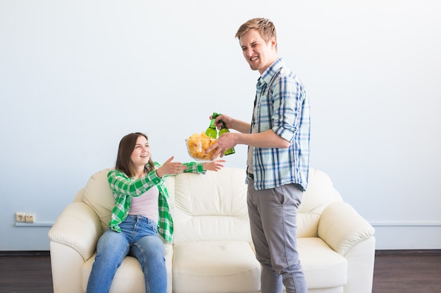 Attractive young loving couple drinking beer at home.