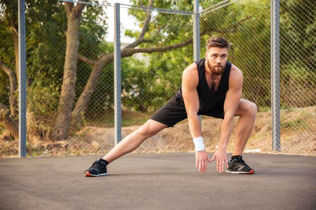 Attractive young male athlete stretching his legs outdoors
