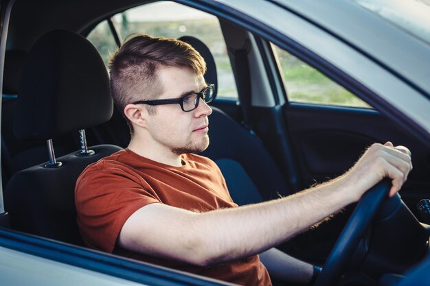 彼の新しい車を運転する魅力的な若い男。