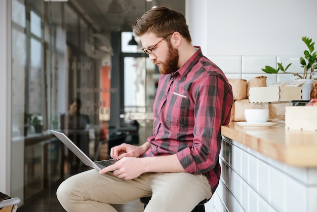 Attractive young man in eyeglasses sitting in cafe