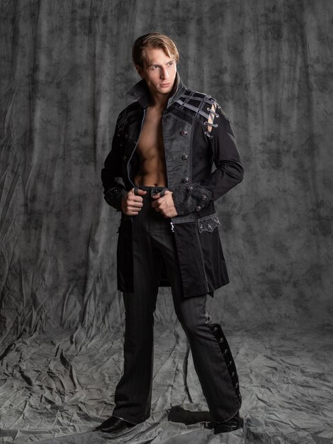 an attractive young man in a fantasy camisole posing in the studio on a gray fabric background