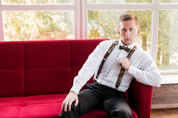 Attractive young man future generation businessman seat on red sofa and interested in searching work