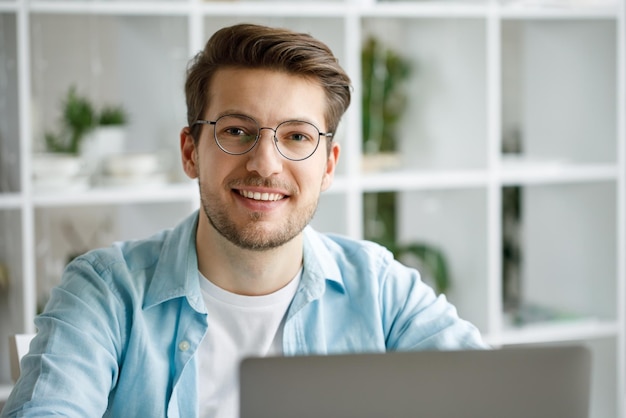 An attractive young man is working on a laptop