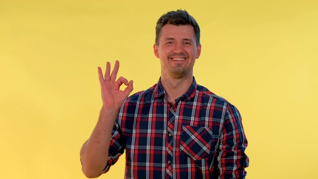 Attractive young man making okay hand sign he making hand gesture on yellow background