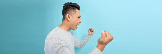 Photo attractive young man screaming and showing fists