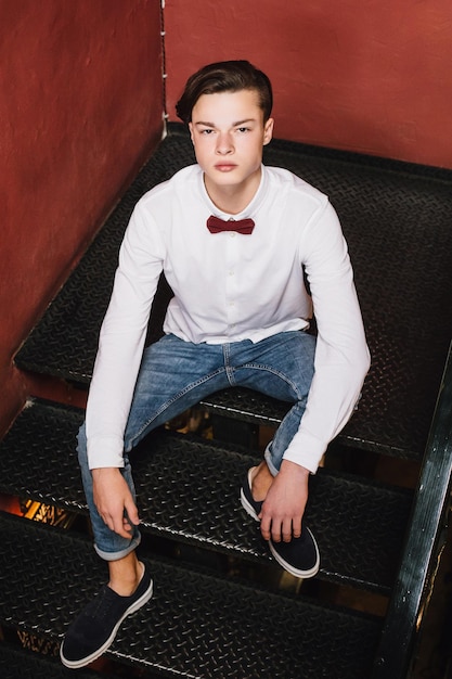 Photo attractive young man sitting on the stairs inside the pub