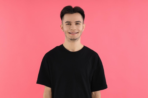 Attractive young man in t-shirt on pink background