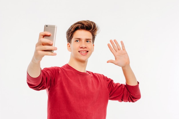 Attractive young man teenager makes a selfie with smartphone on 