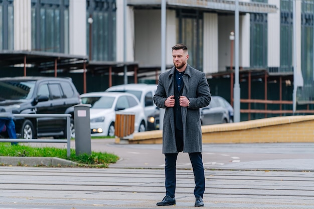 Attractive young man walking in the middle of city street. Crossing the road, looking at side.