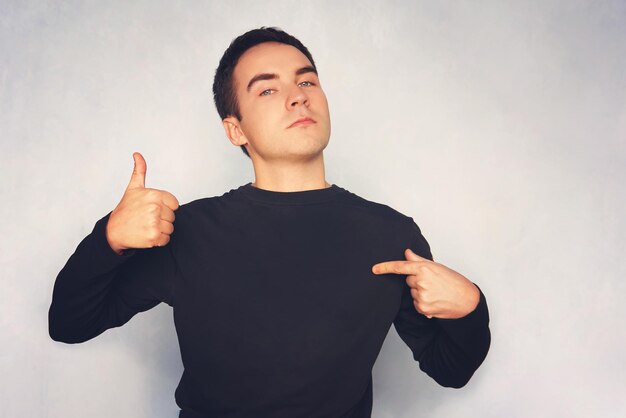 Attractive young man in white tshirt pointing right with his finger