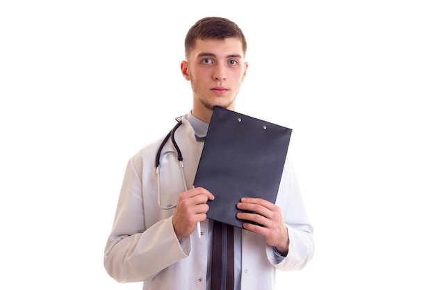Giovane attraente con capelli castani in cravatta blu e abito medico bianco con lo stetoscopio