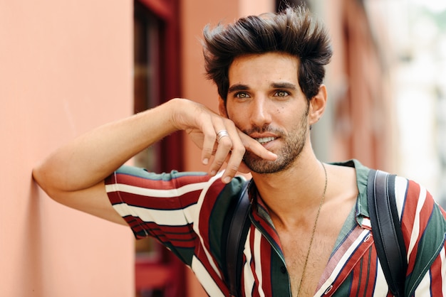 Attractive young man with dark hair and modern hairstyle wearing casual clothes outdoors