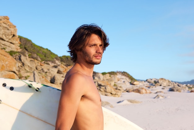 Foto giovane attraente con tavola da surf sulla spiaggia