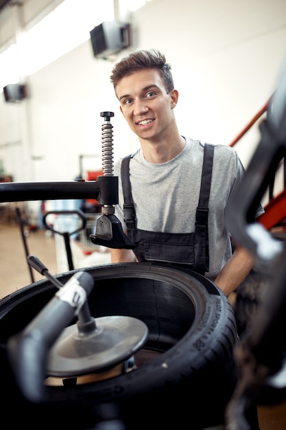 An attractive young mechanic is smiling while working at a car workshop.