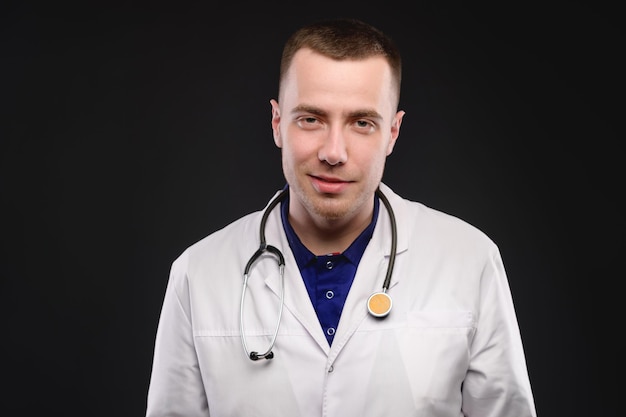 Photo attractive young medical doctor man in a white coat with a stethoscope on his neck friendly medical