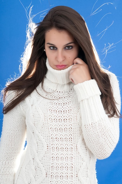 attractive young millennial woman posing on blue background with cold