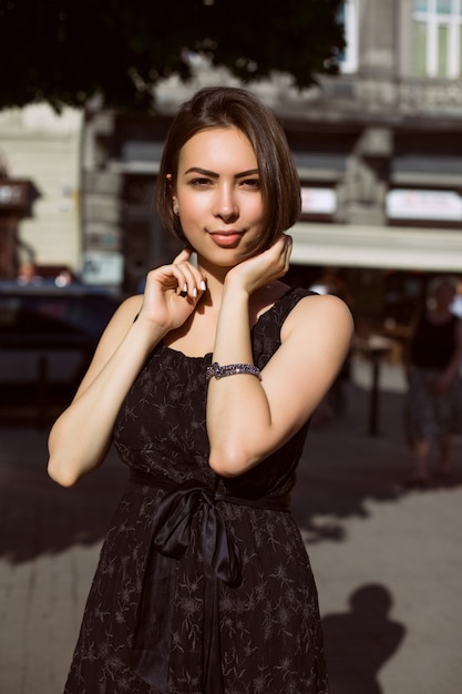 Attractive young model with bronze tan walking on the street and looking to the camera