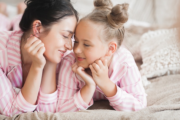 attractive young mother and her little daughter in the bedroom