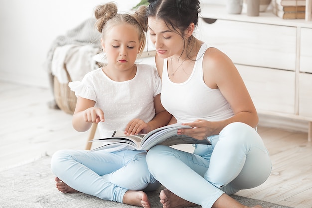 Photo attractive young mother and her little daughter in the bedroom