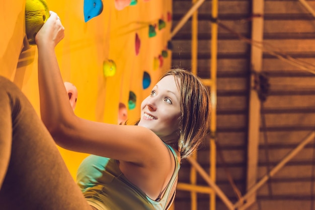 Attractive young professional sport climber woman having training in the gym at artificial wall