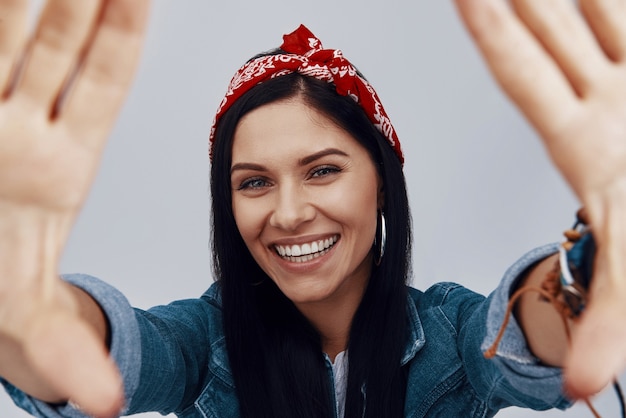 Attractive young smiling woman in bandana  and making hand frame