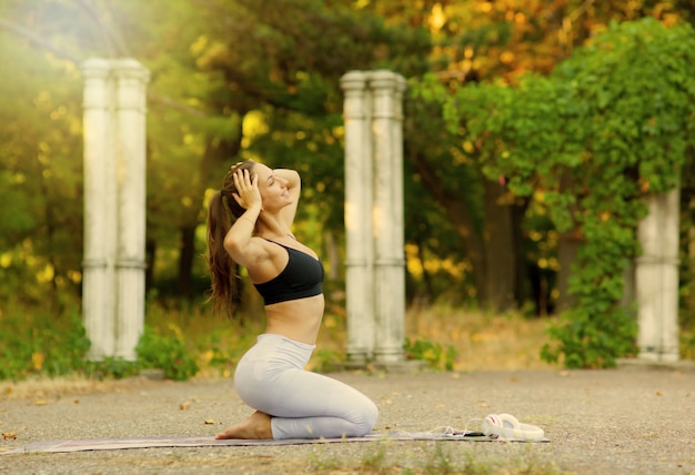 Foto attraente giovane donna sportiva in posa sulla fotocamera mentre è seduta su un tappetino da yoga yoga