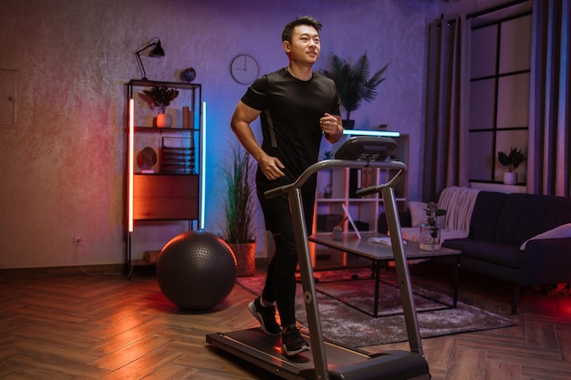 Attractive young sports asian man doing fitness exercise running on treadmill