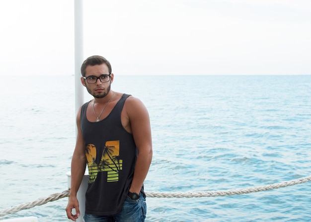 Attractive young sports man standing on a pier by the sea
wearing a tank top