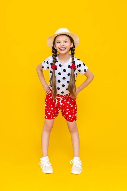 An attractive young teenage girl in a straw hat and summer clothes a girl in a white Tshirt and red shorts on an isolated background a space for copying The concept of summer holidays