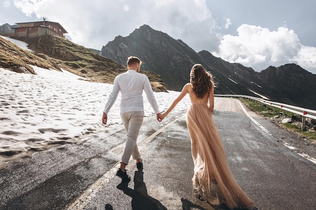 attractive young wedding couple walking at the long road in mountains