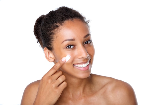 Attractive young woman applying cream on face