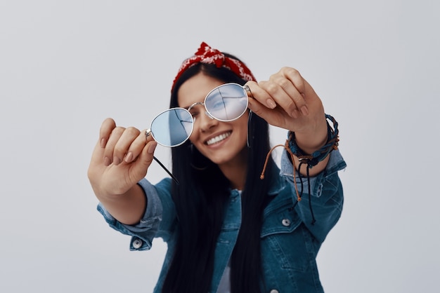 Attractive young woman in bandana holding eyeglasses and smiling