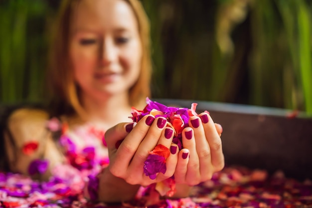 Attractive young woman in bath with petals of tropical flowers
and aroma oils spa treatments for skin rejuvenation alluring woman
in spa salon girl relaxing in bathtub with flower petals
luxury