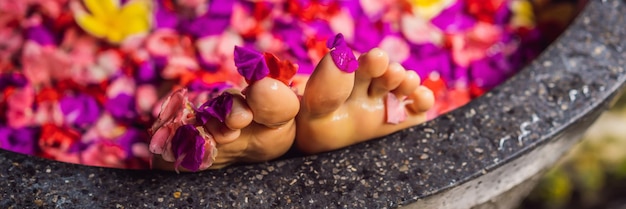 Attraente giovane donna in bagno con petali di fiori tropicali e oli aromatici trattamenti termali per