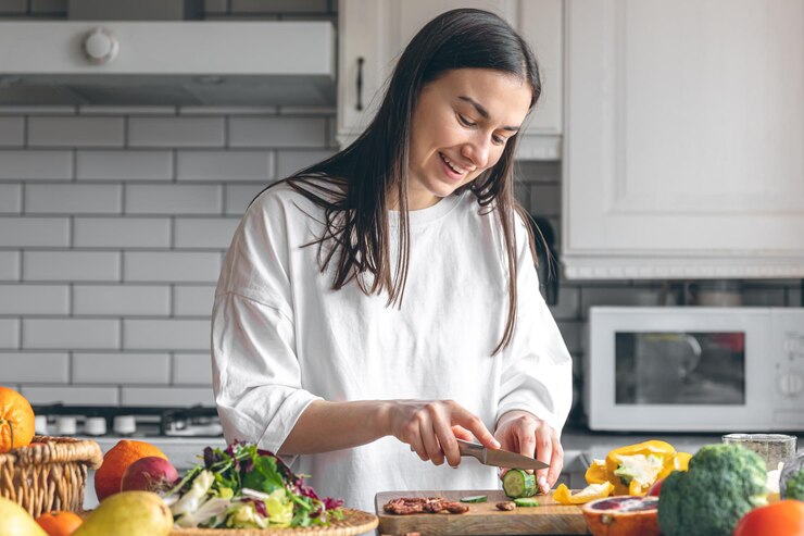 Photo キッチンでサラダ用の野菜を切る魅力的な若い女性