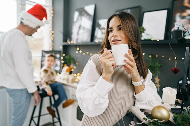 Attractive young woman drinks tea in the kitchen for christmas