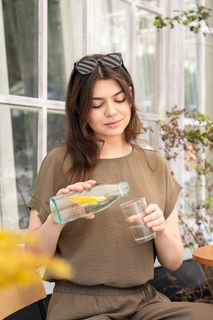 Attractive young woman drinks water with lemon