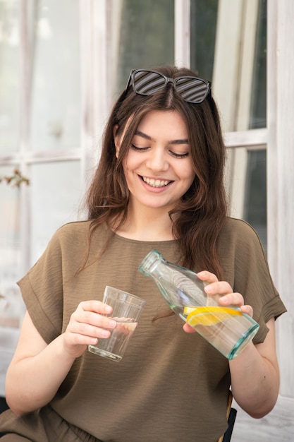 Attractive young woman drinks water with lemon