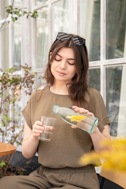 Attractive young woman drinks water with lemon