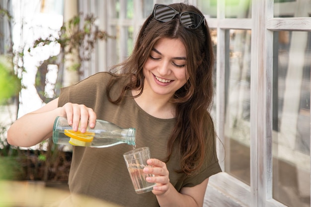 Attractive young woman drinks water with lemon