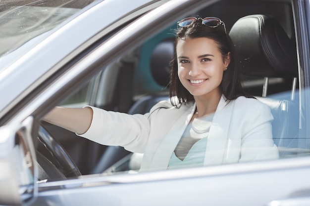 Attractive young woman driving a car. Fancy woman in the automobile. Rich adult female in the car. Confident woman.