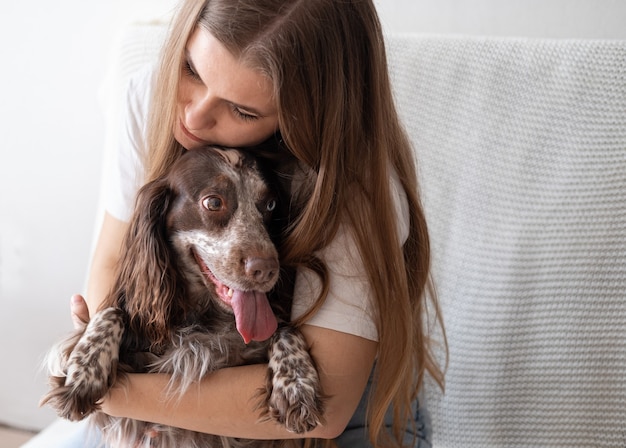 Attractive young woman embrace Russian spaniel dog chocolate merle. Pets care concept.