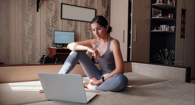 Photo attractive young woman exercising and sitting in yoga lotus position while resting at home